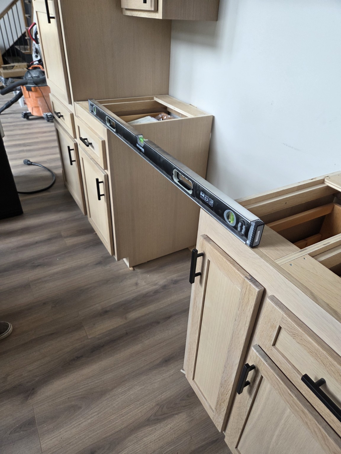 Spirit level spanning an Oak Bay Rock & Tile cabinet installation before countertop templating.