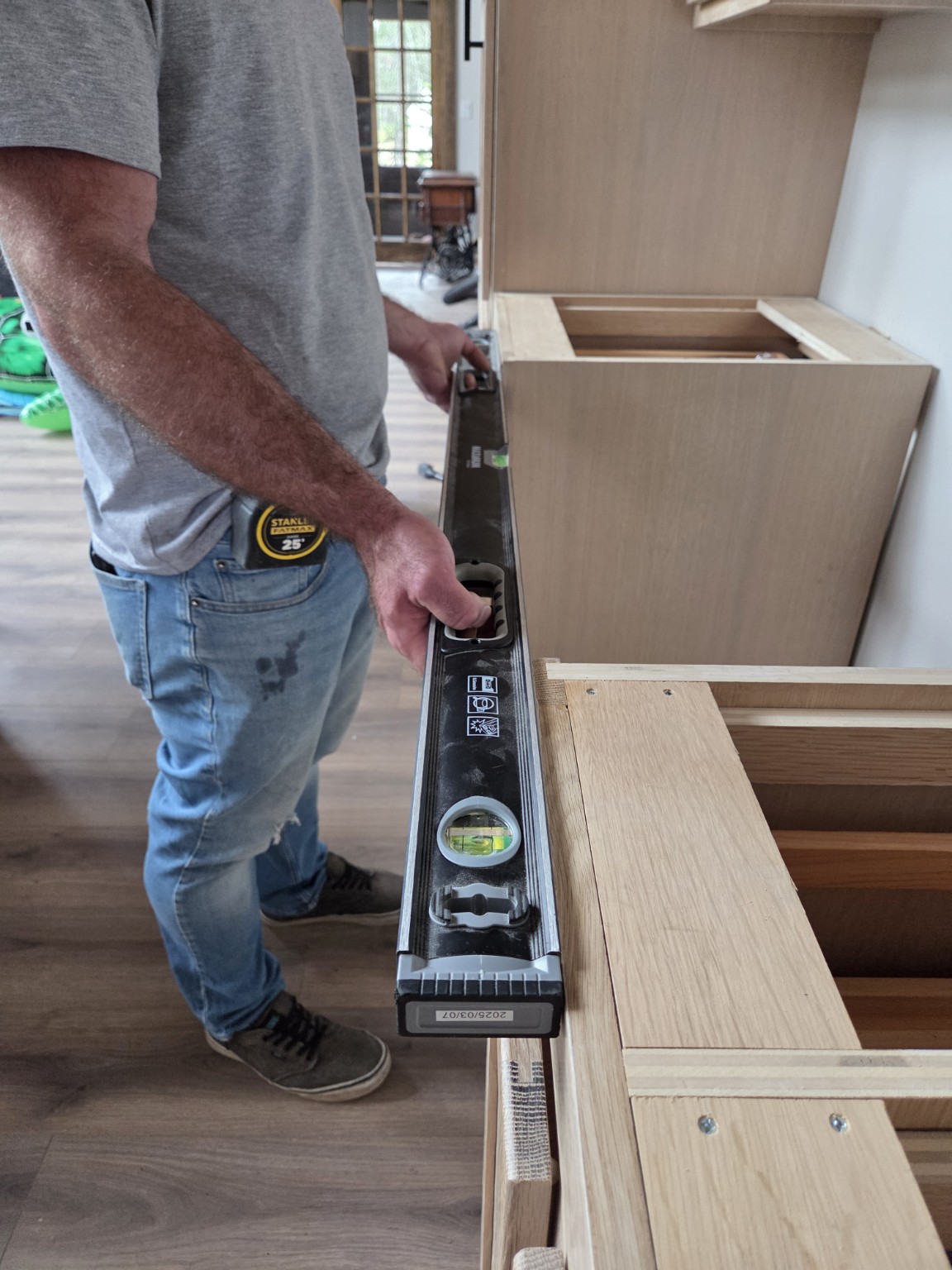 Cabinet installer checking cabinet alignment with a spirit level.