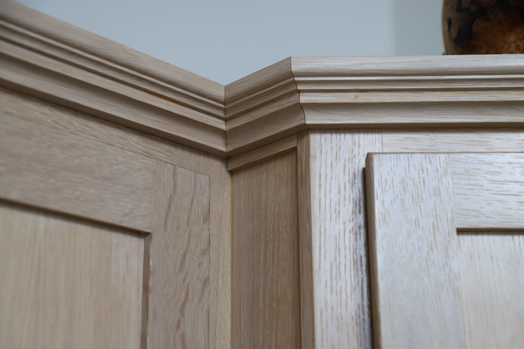Close view of layered crown molding joining two natural wood cabinet runs.