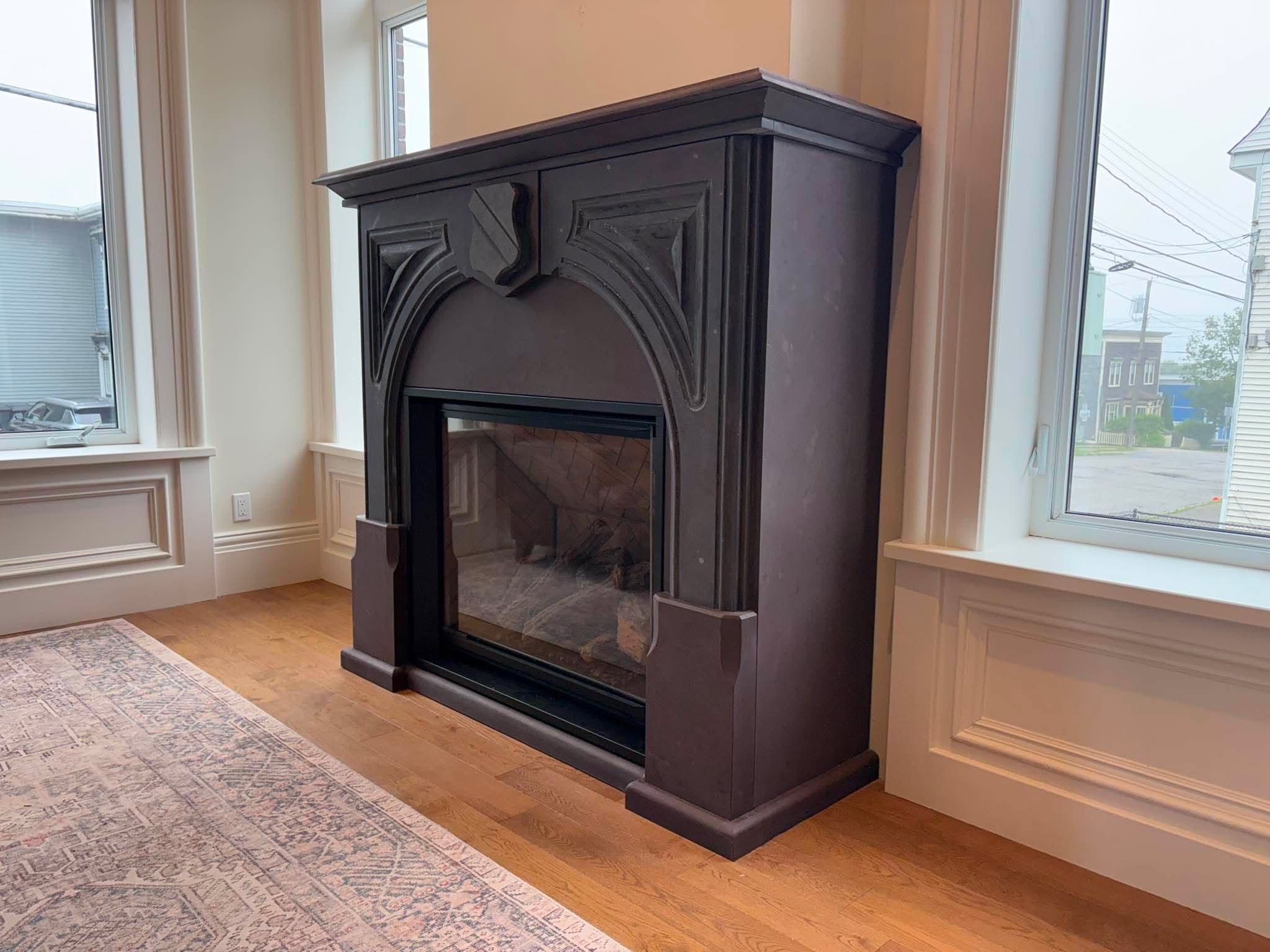 Dark custom stone fireplace surround with carved architectural detailing.