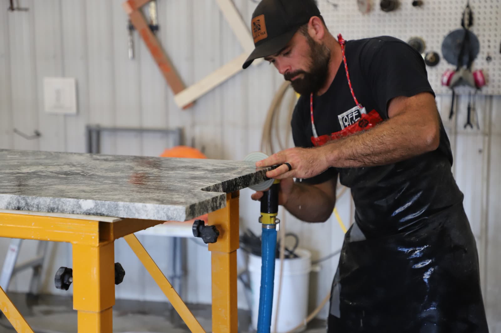 Craftsman hand-finishing the edge of a custom stone countertop in the Oak Bay Rock & Tile workshop.