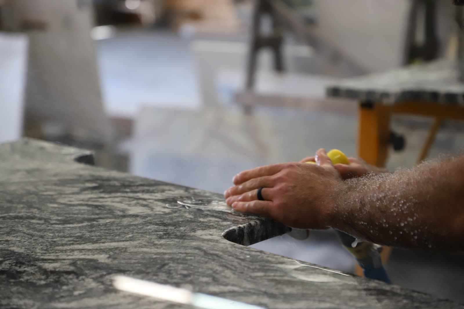 Craftsman hand-finishing a custom opening in a stone countertop.