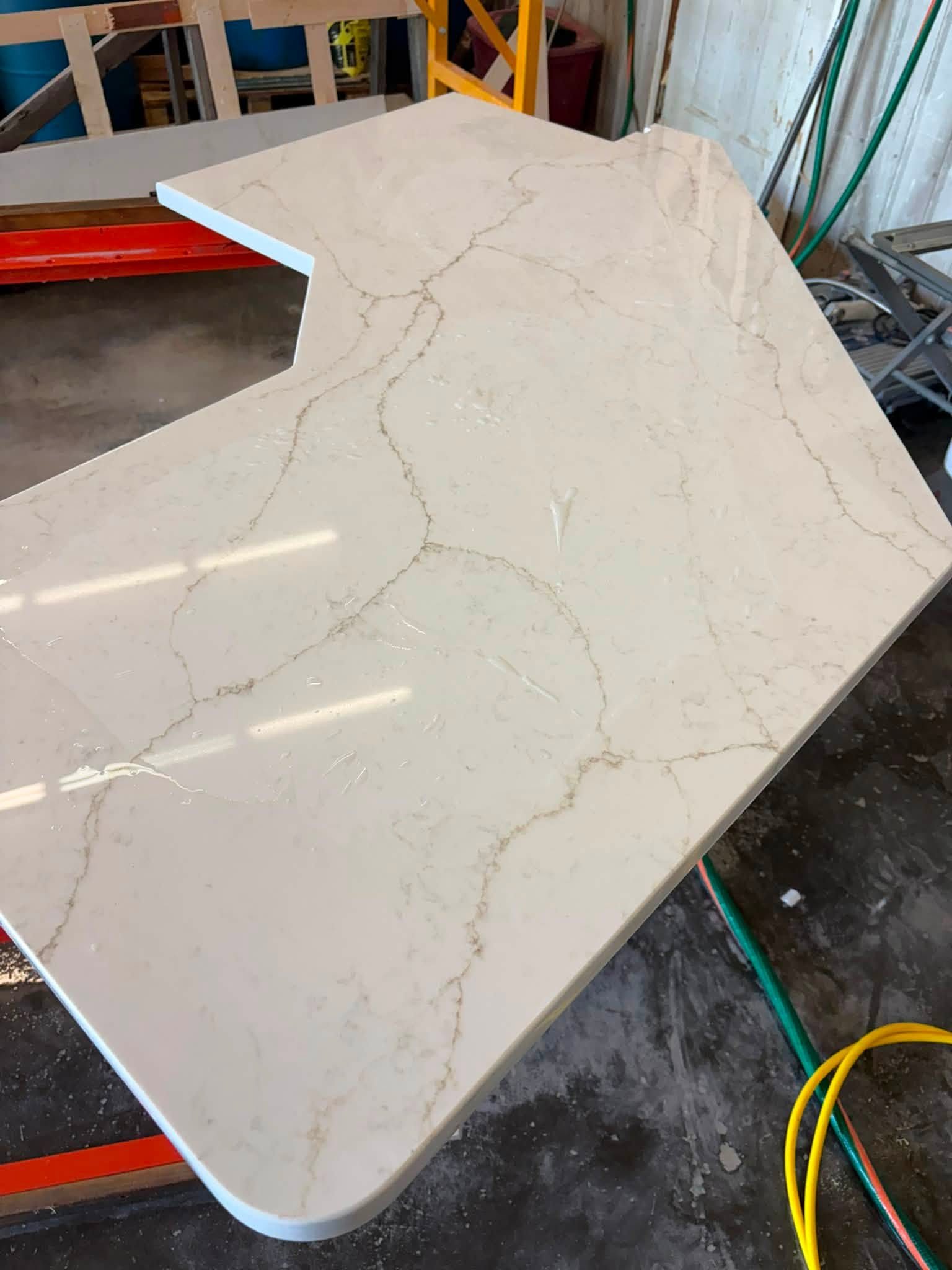 Fabricated countertop piece with cutout and rounded corner resting on shop supports.