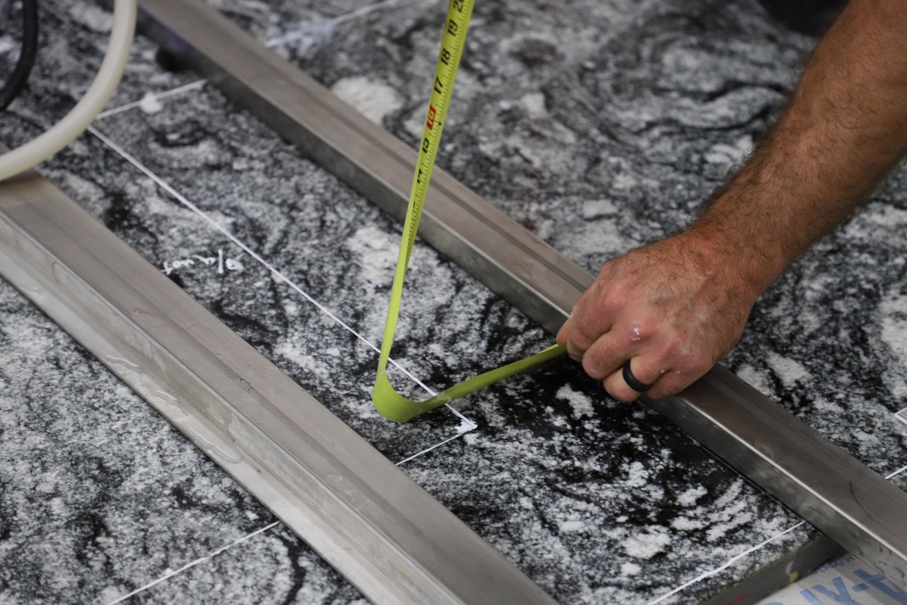 Worker verifying measurements marked on a stone slab before cutting.