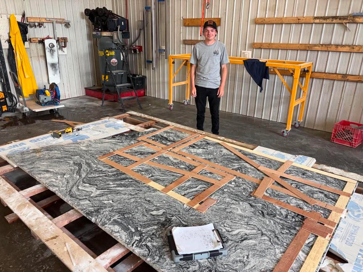 Physical wooden countertop templates laid out on a full granite slab in the shop.