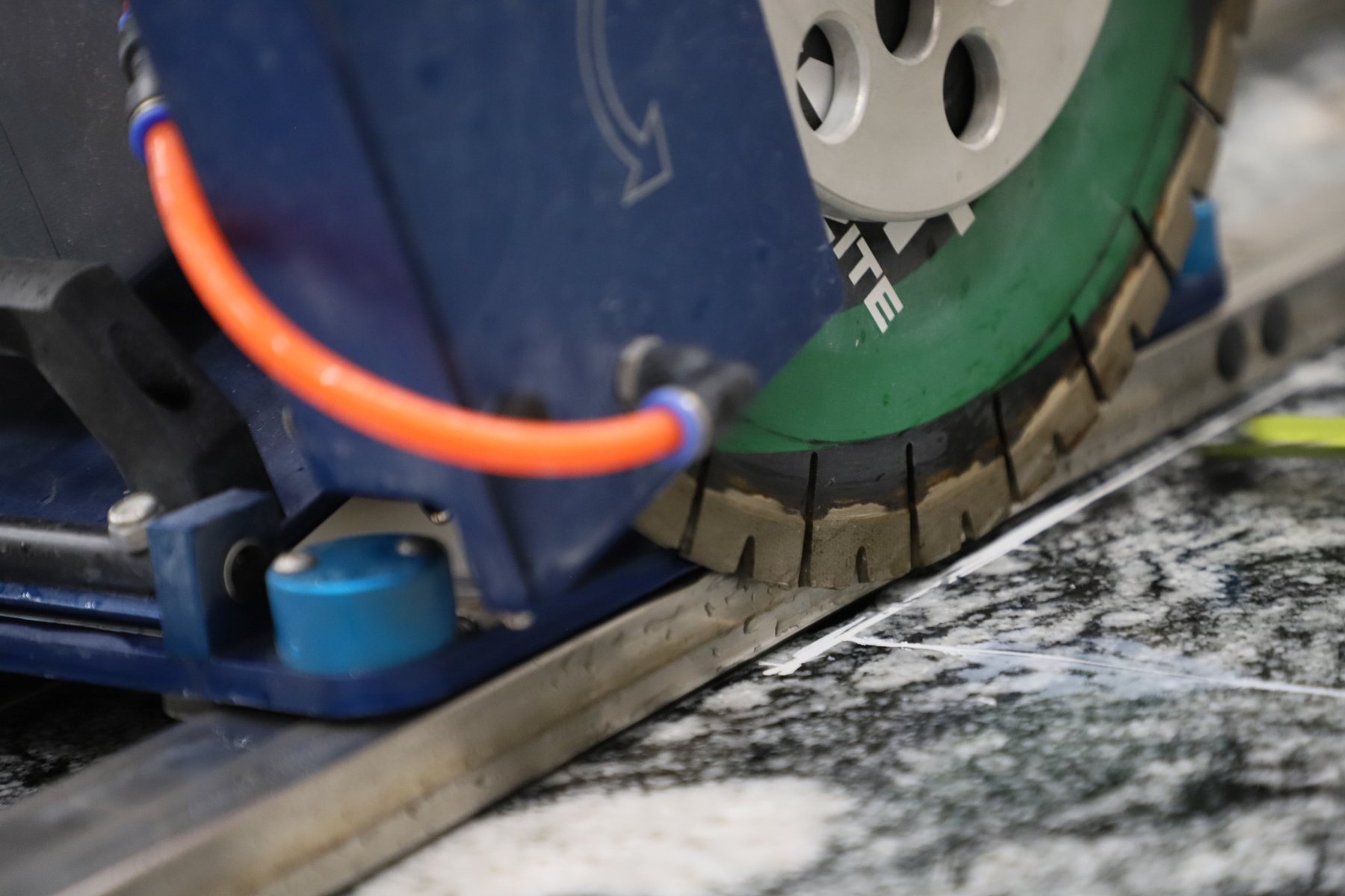 Guided stone saw cutting a marked stone slab in the fabrication shop.
