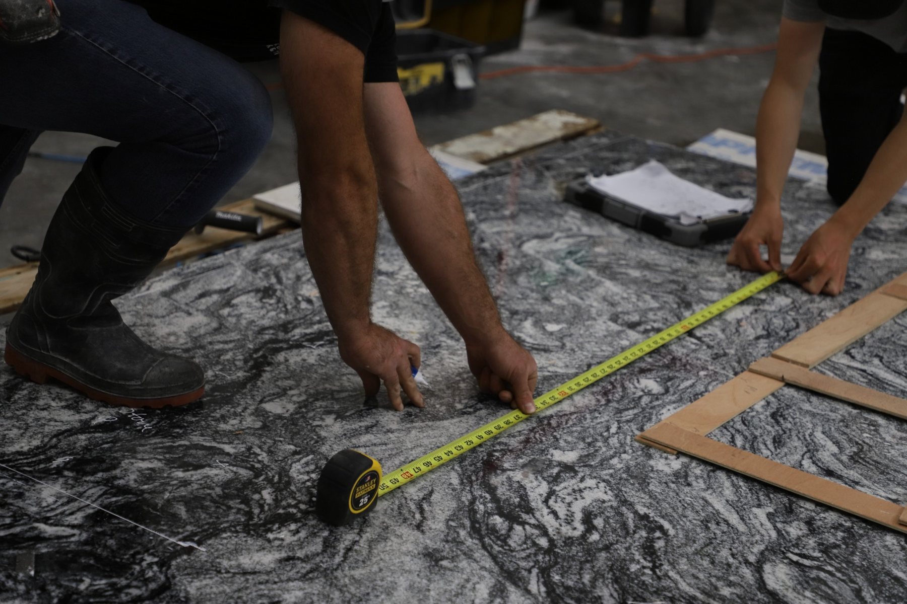 Oak Bay Rock & Tile team carefully measuring a stone slab before fabrication.
