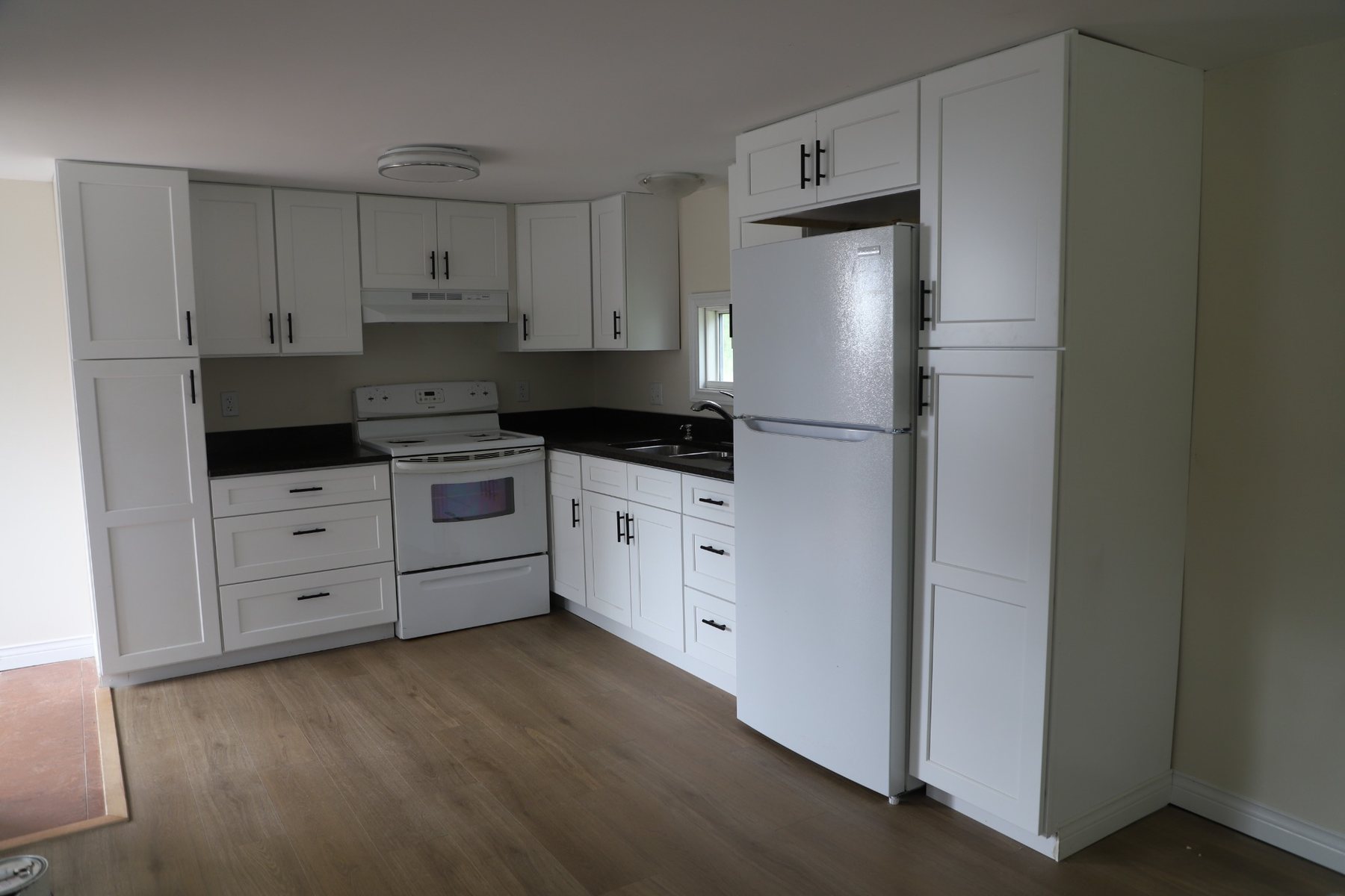Dark stone kitchen with white cabinetry — wide view.