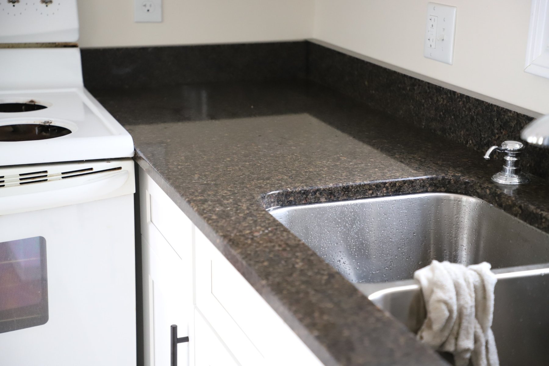 Sink area with dark stone countertop and stone backsplash detail.