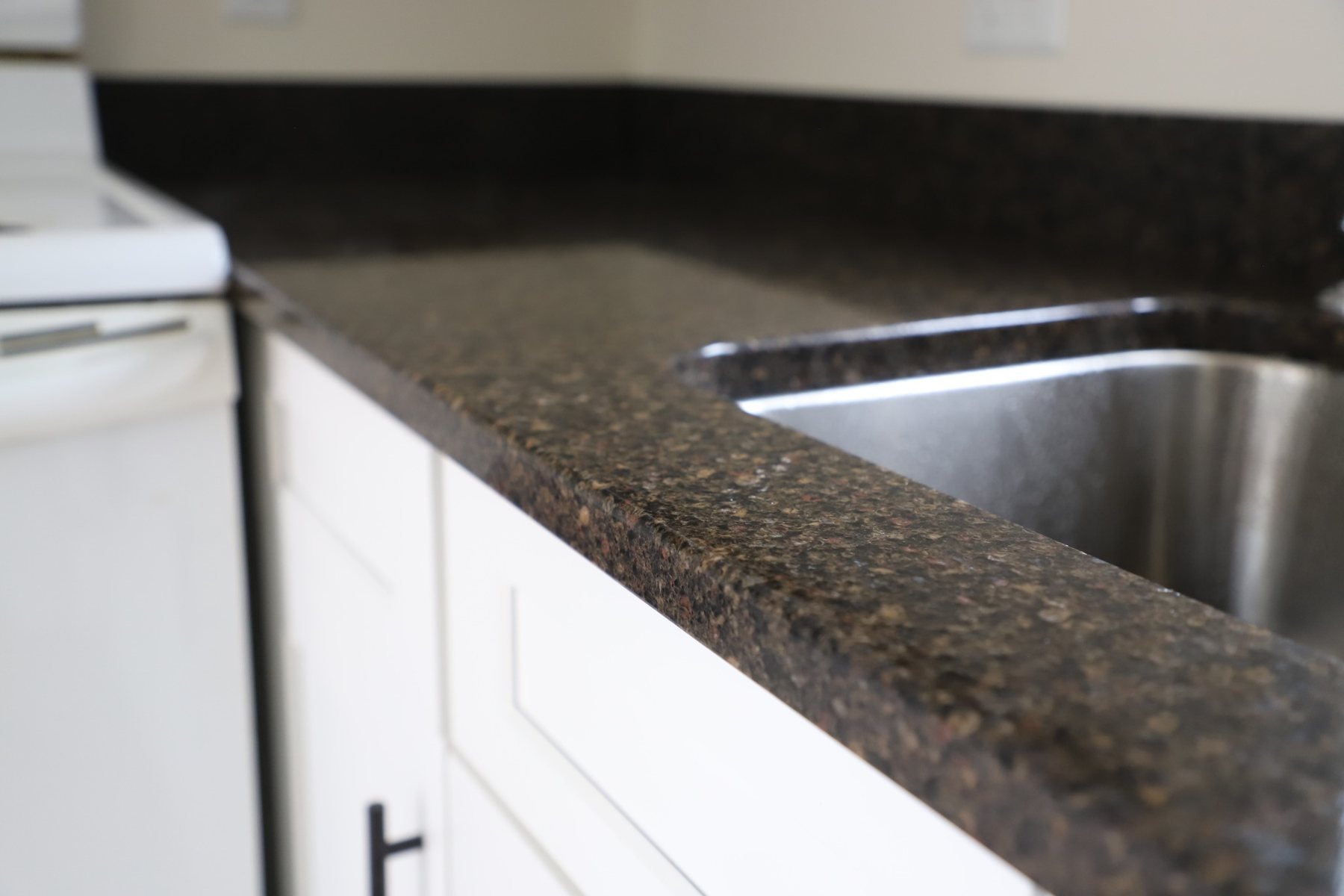 Polished edge and undermount sink detail on dark stone countertop.