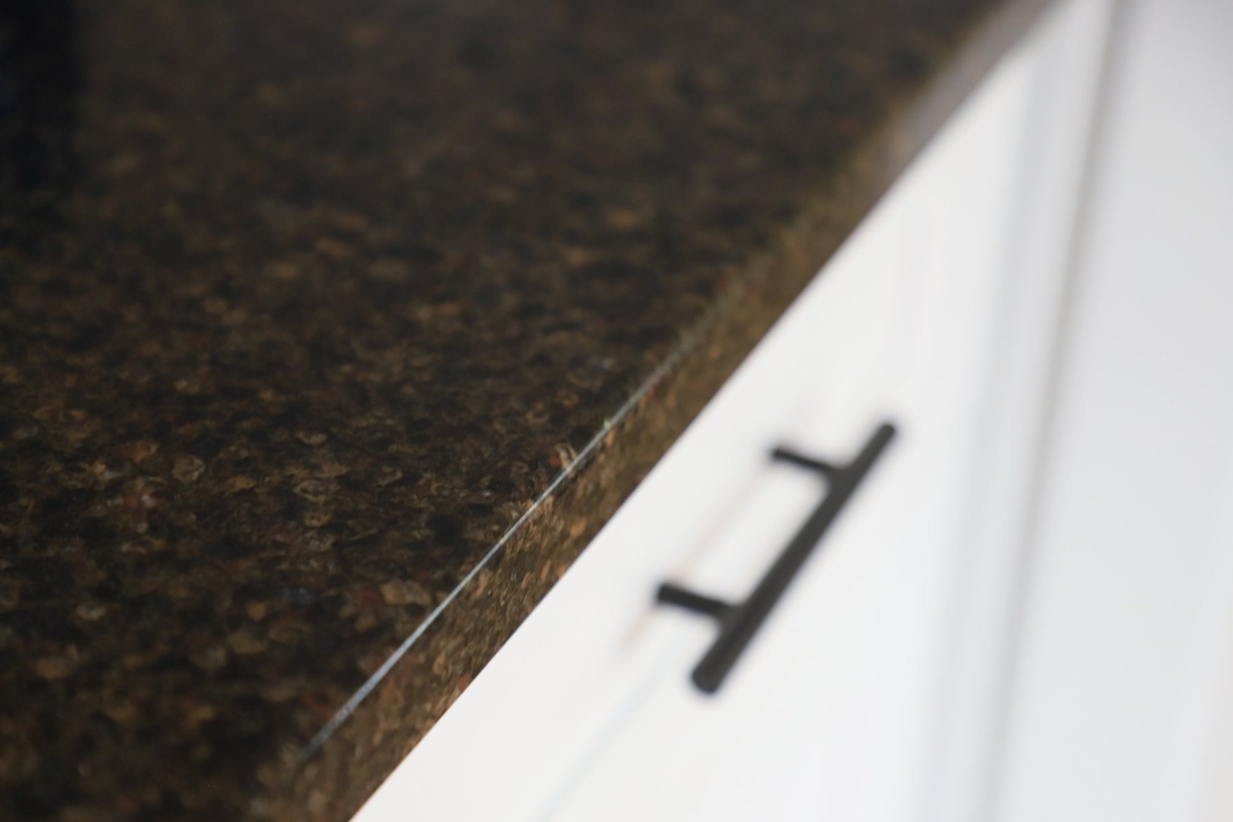 Dark stone edge profile against white cabinetry.