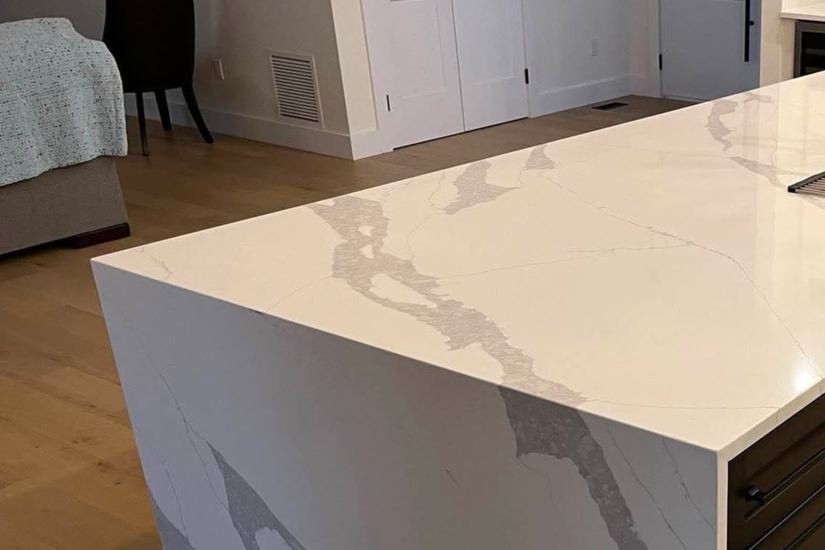 Large white stone kitchen island with full waterfall end detail.